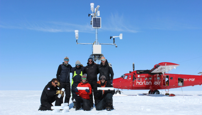 meteorologists in front of a weather station with plane